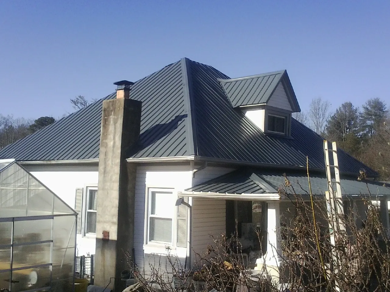 Dark blue standing seam metal roof on a white farmhouse with dormer — Slate & Tile Roof Repair by Roofing Brothers in Boones Mill