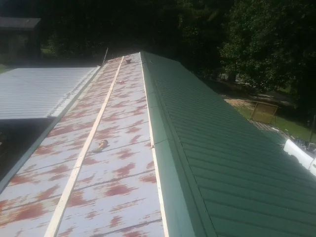 Old rusted panels beside newly installed green metal roofing — Wind Damage Roof Repair by Roofing Brothers in Boones Mill