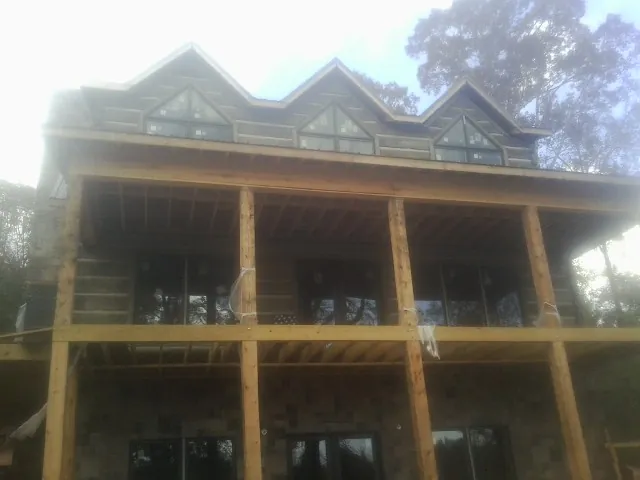 Dormers and porch framing on a large log home under construction — Roof Coating work by our crew in Boones Mill