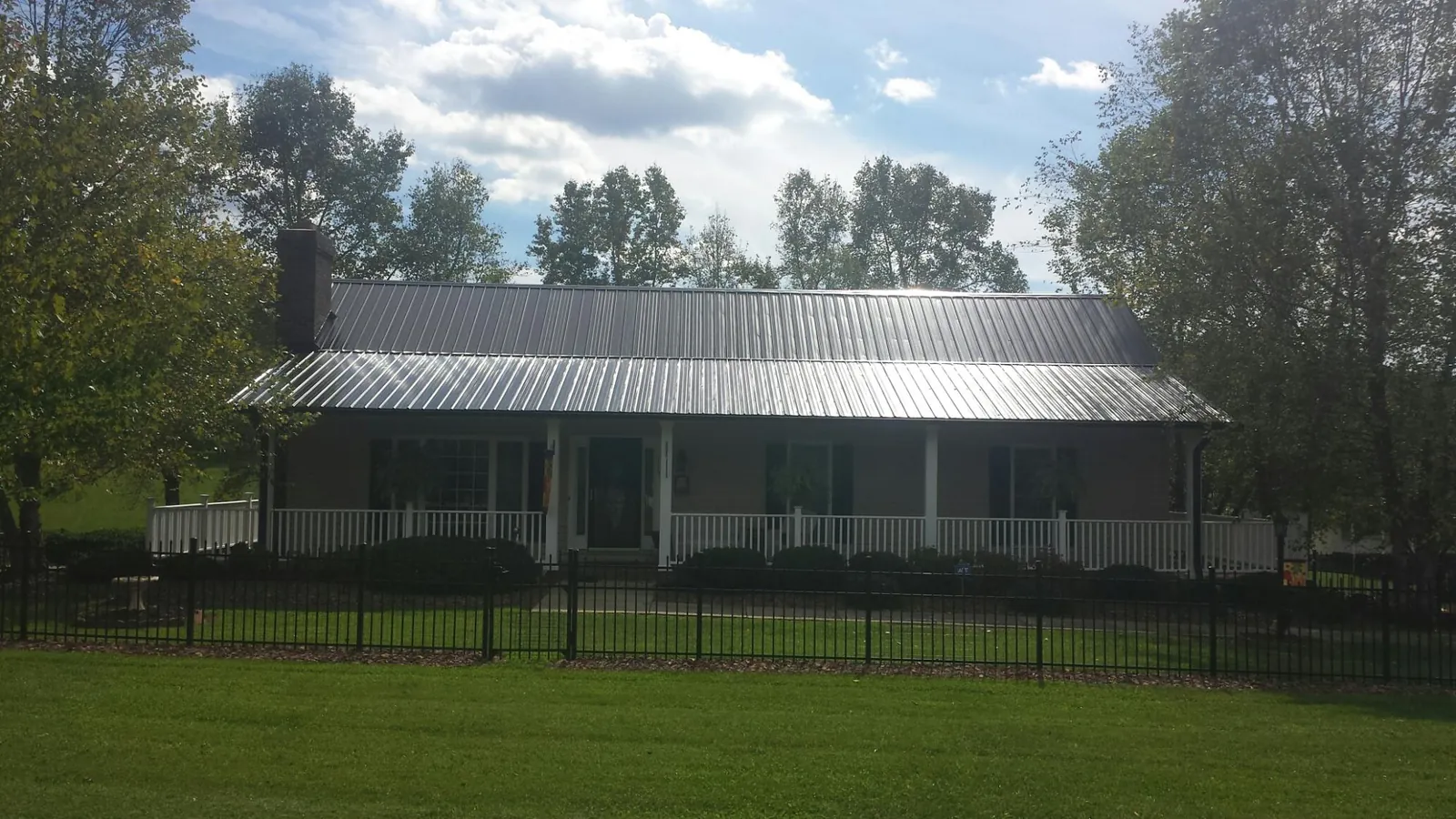 Gray metal roof on a brick ranch with a full width front porch — Gutter Guard Installation work by our crew in Boones Mill