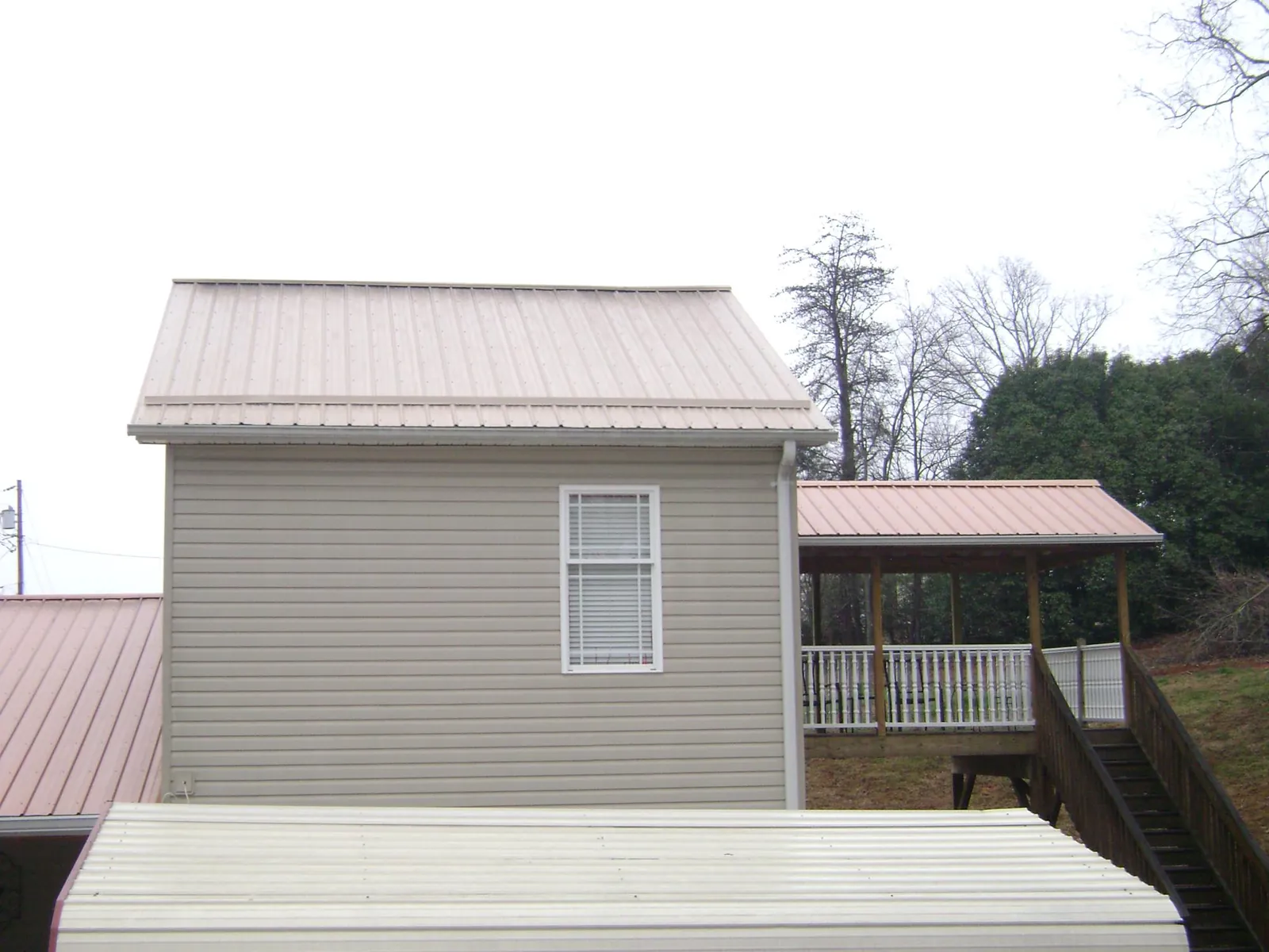 Tan metal roofs on a two story addition and attached porch, from a Roof Replacement job in Boones Mill