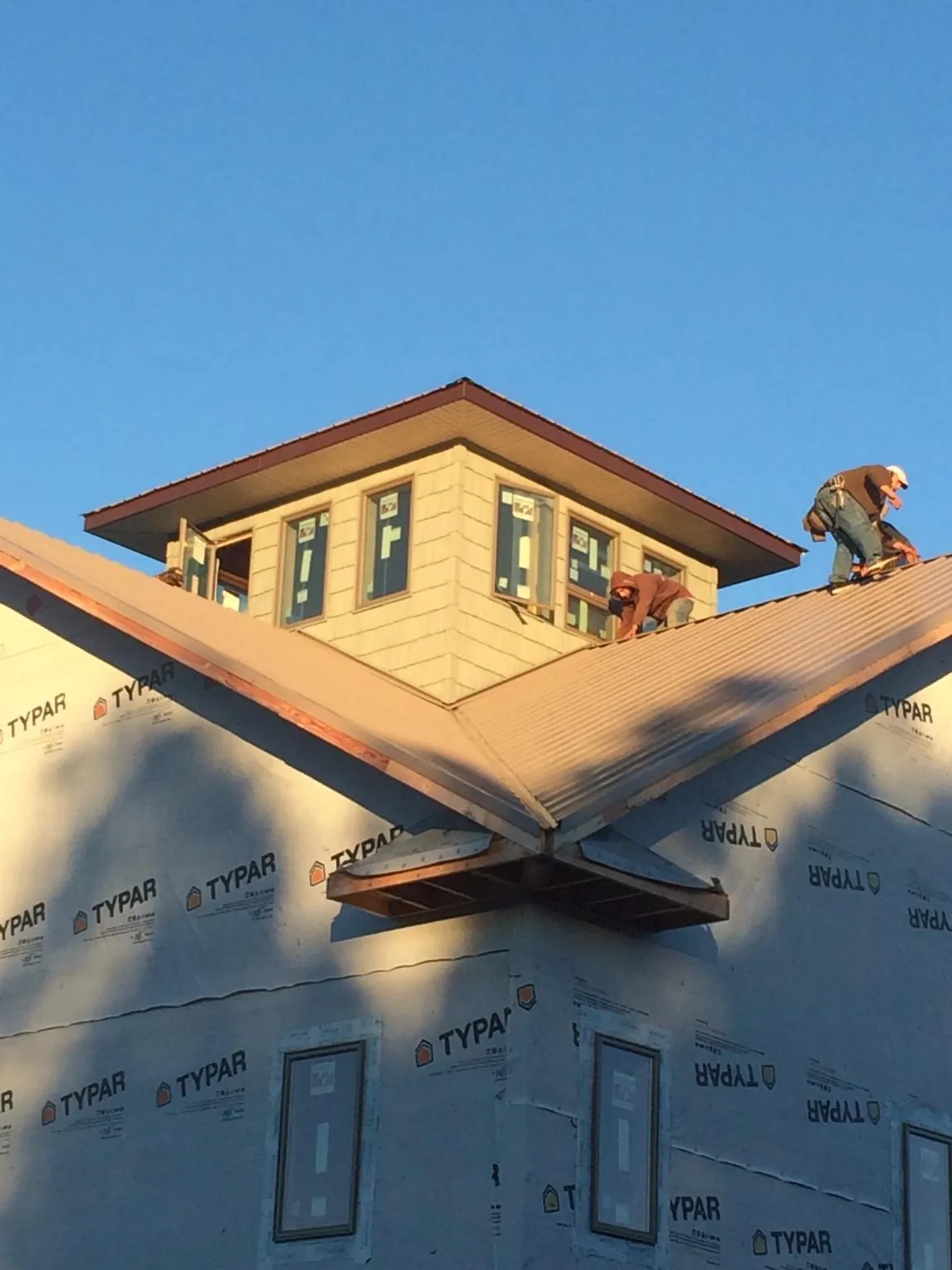 Roofers working around a rooftop cupola on a new metal roof at sunset — Roof Waterproofing in Boones Mill by Roofing Brothers